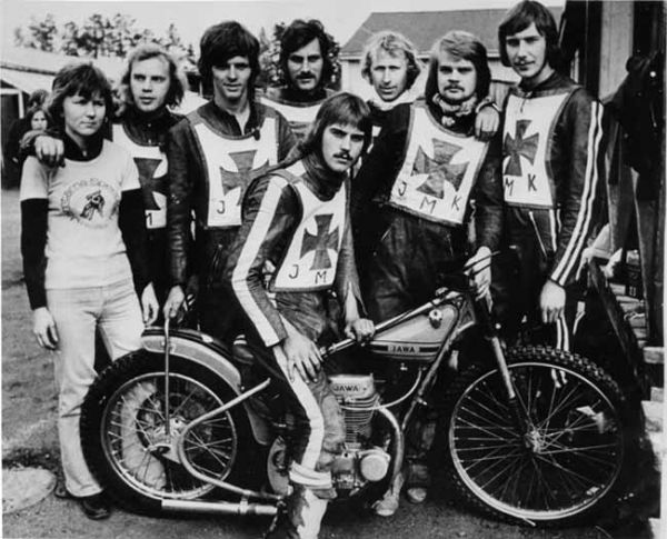 Jämtarnas div III-lag 1974
Jämtarna 1974 Anna-Lena Hjalmarsson (lagl.) Börje Sjöbom, Rolf Fridh, Hasse Decker, Torbjörn Dannö, P-O Gudmundsson, Roland Pålsson och Åke Fridell (sittande på cykeln).
Jag var med och arrangerade den här bilden. Fotografen jag hade med mig, Anders Arab tog originalbilden. Jag frilansade för Alllt om MC och lokaltidningen hemma i Sundsvall.
Jag var där för att bevaka tävlingen som var ett kval till division två mot Masarna. Masarna vann och gick upp i tvåan.
Min färdkamrat Börje Sjöbom körde in i planket i början av tävlingen och fick tillbringa natten på Östersunds lasarett. Även Totto Dannö hade en tung dag vad jag minns. (TL)
